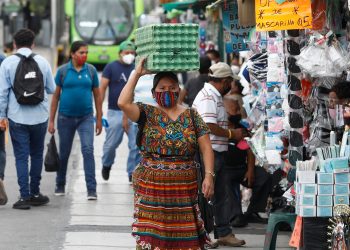 Personas caminando en la calle con mascarilla
