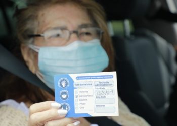 Olga González, de 80 años, muestra su carné de vacunación.