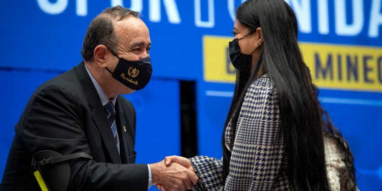 El presidente Alejandro Giammattei, saluda a una de las beneficiarias con la beca de atencion integral de enfermería.