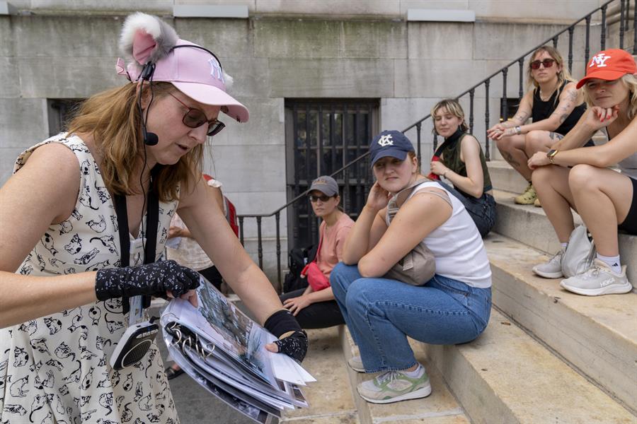 La escritora Peggy Gavan muestra la foto de un gato mientra cuenta una historia a un grupo de turistas que hace el recorrido.