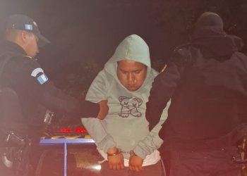 Agentes de la Policía Nacional Civil conducen a uno de los presuntos secuestradores de migrantes.