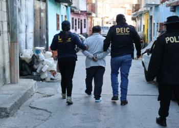 Agentes conducen a uno de los capturados por homicidio y homicidio en grado de tentativa.