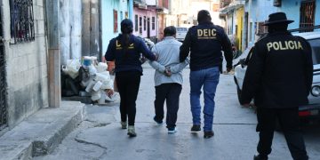 Agentes conducen a uno de los capturados por homicidio y homicidio en grado de tentativa.