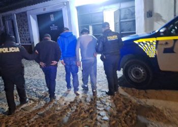 Agentes de la PNC conducen a detenidos por el robo de un cabezal con furgón cargado de maíz, frijol y aceite.