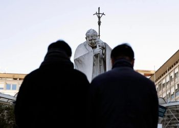 Feligreses continúan llegando a orar por la salud del papa Francisco frente un monumento a san Juan Pablo II frente al hospital Gemelli de Roma.