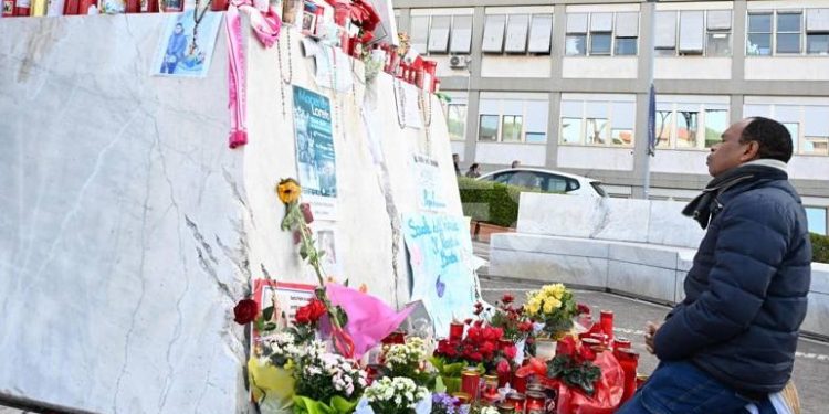 Un feligrés ora junto a un altar improvisado a los pies de un monumento al papa Juan Pablo II afuera del Hospital Policlínico Gemelli, donde Francisco cumple 19 días internado.