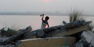 Un niño trata de liberar paso fluvial de escombros del terremoto en Birmania. / Foto: EFE.