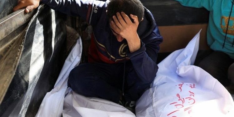 Un hombre llora junto a los cuerpos de familiares en Gaza.