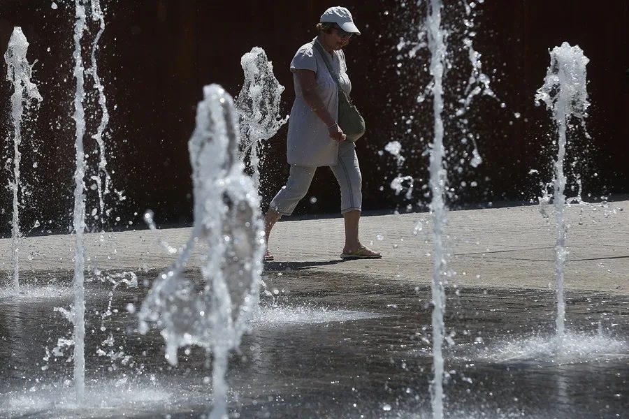 Una mujer se refresca junto a una fuente en Atenas, Grecia.