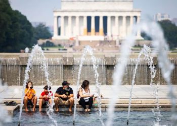 Una familia se refresca por el intenso calor durante una visita a monumentos en Washington.