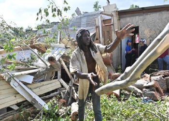 Un jamaicano trata de despejar lo que quedó de su vivienda que quedó destruida al caerle un árbol por el paso del huracán Melissa.