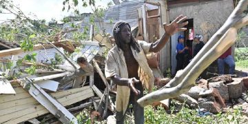 Un jamaicano trata de despejar lo que quedó de su vivienda que quedó destruida al caerle un árbol por el paso del huracán Melissa.