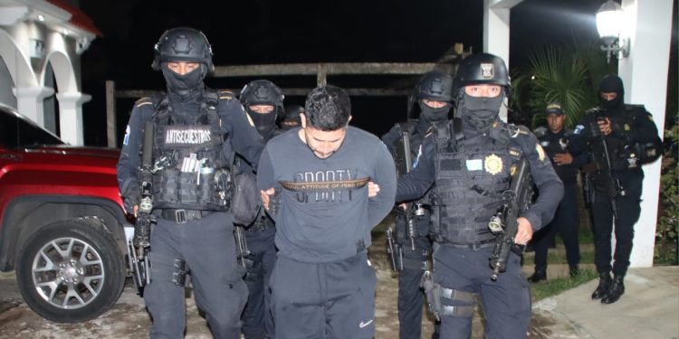 Agentes del Comando Antisecuestros de la PNC conducen al presunto secuestrador luego del rescate de la víctima.