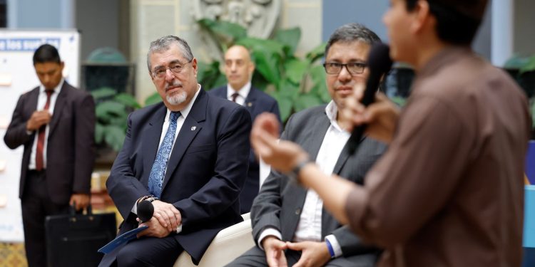 El presidente Bernardo Arévalo y el titular de Segeplan, Carlos Mendoza, escuchan el testimonio de un joven beneficiario del programa Becas por nuestro futuro.