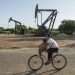 Una mujer conduce junto a un niño una bicicleta frente a balancines petroleros este jueves, en Cabimas (Venezuela). / Foto: EFE.