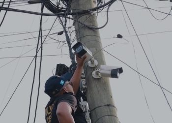Agente de la PNC desinstala una de las cámaras de video vigilancia en la aldea Lo de Rodríguez, en la zona 18.