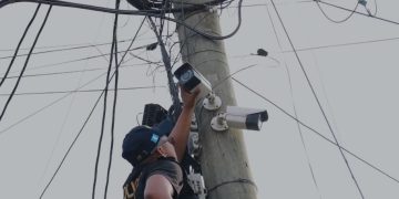 Agente de la PNC desinstala una de las cámaras de video vigilancia en la aldea Lo de Rodríguez, en la zona 18.