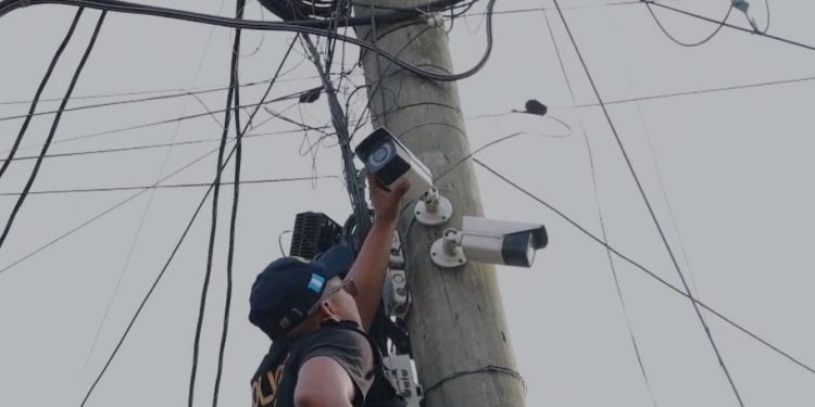 Agente de la PNC desinstala una de las cámaras de video vigilancia en la aldea Lo de Rodríguez, en la zona 18.