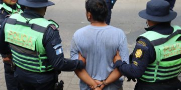 Agentes de la PNC conducen a uno de los presuntos asaltantes capturados en la carretera a El Salvador.