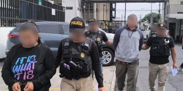 Investigadores de la DEIC conducen a dos de los detenidos en allanamientos.