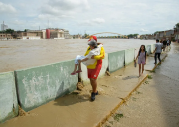 Fotografía de archivo de un salvavidas de la Policía Nacional cargando a una anciana por un costado del canal del río Piura, en Piura (Perú). EFE/ Edwin Zapata