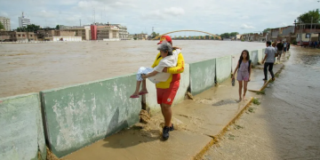 Fotografía de archivo de un salvavidas de la Policía Nacional cargando a una anciana por un costado del canal del río Piura, en Piura (Perú). EFE/ Edwin Zapata