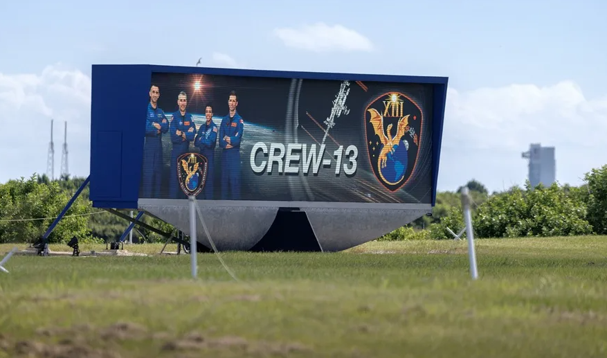 El reloj de cuenta atrás de la zona de prensa de la NASA muestra el logotipo de la misión y los retratos de la tripulación