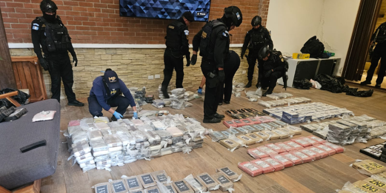 Agentes de la PNC y personal del MP examinan paquetes localizados durante el desmantelamiento del narcolaboratorio. / Foto: MP