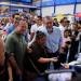 Una beneficiaria sostiene una tarjeta junto al presidente Bernardo Arévalo y al ministro Abelardo Pinto durante la actividad de Bolsa Social.