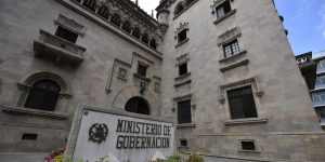 Fachada del Ministerio de Gobernación, con ventanas ornamentadas y un rótulo con el nombre de la institución en primer plano.
