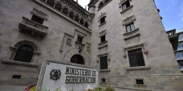 Fachada del Ministerio de Gobernación, con ventanas ornamentadas y un rótulo con el nombre de la institución en primer plano.