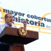 Presidente Bernardo Arévalo habla desde un podio con el escudo nacional, frente a una pantalla sobre la cobertura de Bolsa Social.