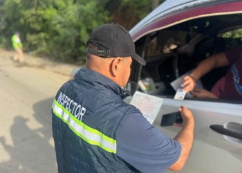 Un inspector revisa documentos que le presentan desde la ventana de un vehículo durante un control en carretera.