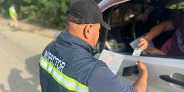Un inspector revisa documentos que le presentan desde la ventana de un vehículo durante un control en carretera.