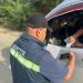 Un inspector revisa documentos que le presentan desde la ventana de un vehículo durante un control en carretera.