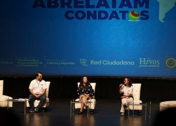 Tres panelistas conversan en un escenario frente a una pantalla con el nombre de Abrelatam/ConDatos.