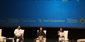 Tres panelistas conversan en un escenario frente a una pantalla con el nombre de Abrelatam/ConDatos.