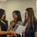 Una mujer recibe un diploma de manos de otra, acompañadas por dos personas durante una actividad institucional.