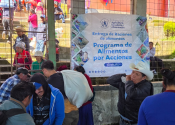Personas trasladan sacos junto a una manta del MAGA que anuncia la entrega gratuita de alimentos del programa Alimentos por Acciones.