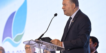 Representante del MEM habla ante un micrófono desde un atril transparente durante la presentación de la PEG-6-2026.