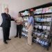Bernardo Arévalo conversa con personal de Proam junto a estanterías con medicamentos.