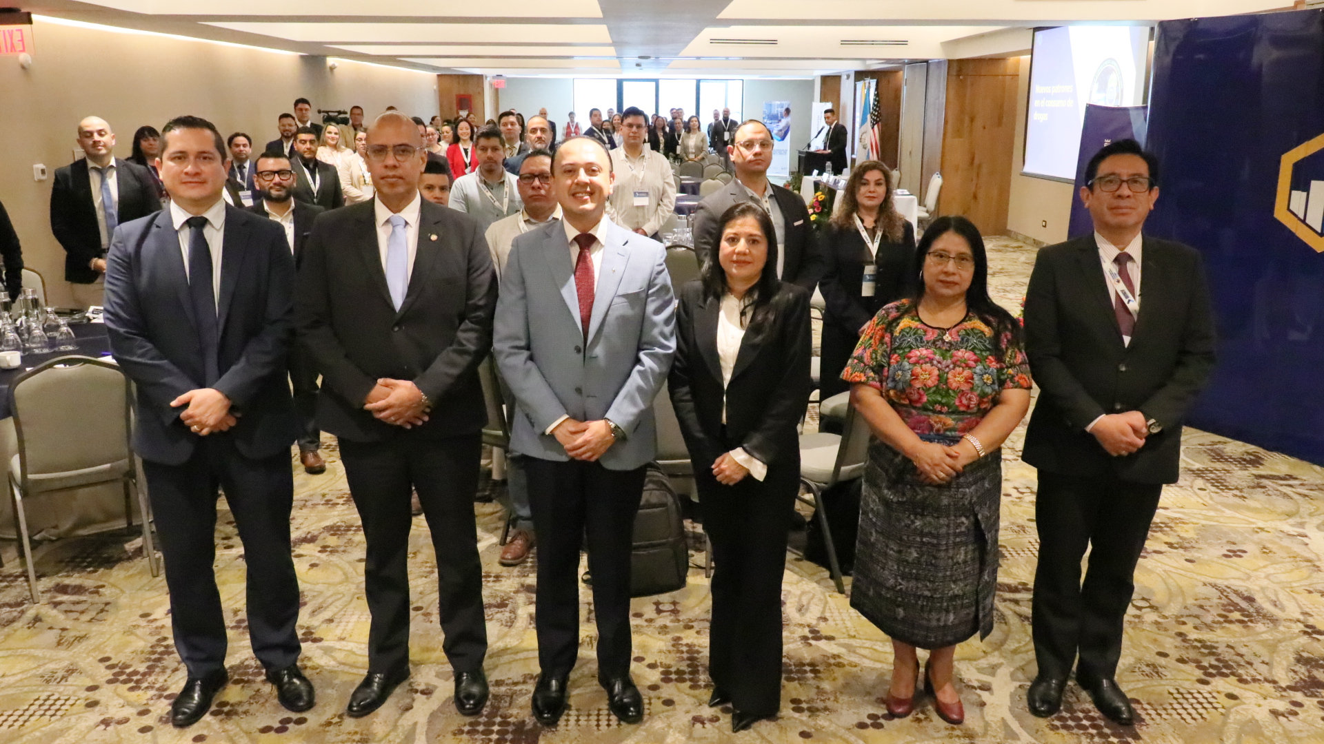 Participantes del congreso sobre precursores químicos posan de pie para una fotografía grupal en el salón del encuentro.