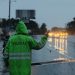 Brigadista de Provial dirige el tránsito vehicular bajo la lluvia en una carretera mojada.