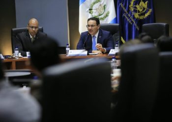 Marco Antonio Villeda habla ante un micrófono durante una reunión, frente a los asistentes y junto a otro participante.