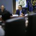 Marco Antonio Villeda habla ante un micrófono durante una reunión, frente a los asistentes y junto a otro participante.