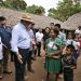 El presidente Bernardo Arévalo conversa con una mujer junto a un niño, frente a viviendas con techos de palma.
