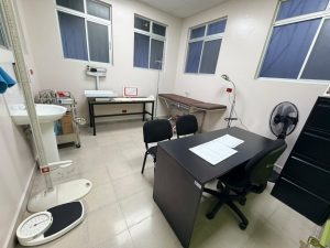 Consultorio equipado con camilla, escritorio, sillas, básculas y lavamanos.