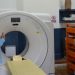 Joaquín Barnoya escucha a un acompañante junto a un tomógrafo y su camilla en el Hospital de Mazatenango.