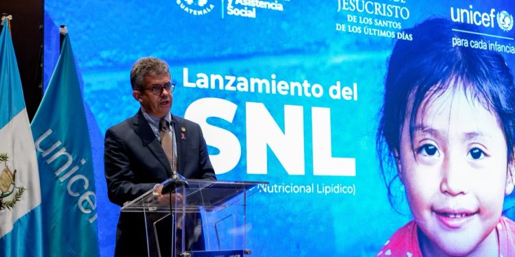 Joaquín Barnoya habla desde un atril frente a una pantalla que anuncia el lanzamiento del suplemento nutricional lipídico.
